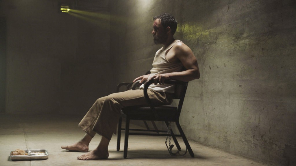 Naser Salaam (Omid Abtahi) est assis sur une chaise dans sa cellule de prison.