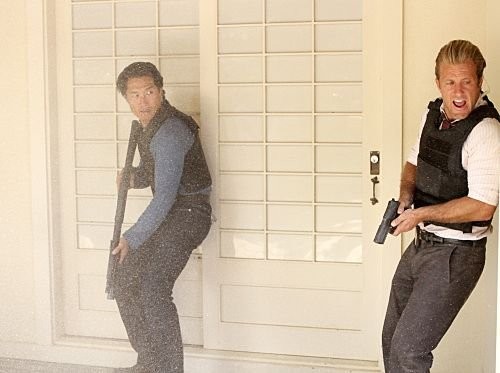 Chin Ho Kelly (Daniel Dae Kim) & Danny Williams (Scott Caan) sont armés et s'apprêtent à rentrer dans une maison.