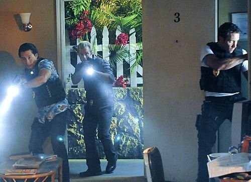 En pleine nuit, trois des membres du 5-0 entrent dans la maison d'un suspect munis de lampes torches.