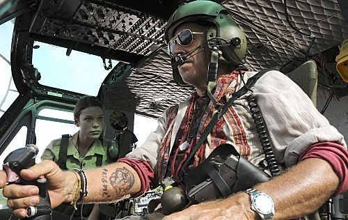 Frank Bama (Jimmy Buffett) pilote l'hélicoptère dans lequel se trouve Lori Weston (Lauren German).