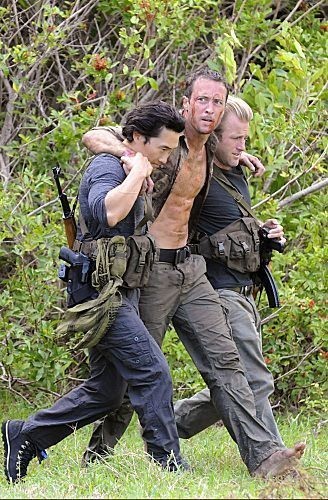 Danny Williams (Scott Caan) & Chin Ho Kelly (Daniel Dae Kim) aident Steve McGarrett (Alex O'Loughlin) à marcher jusqu'à l'hélicoptère.