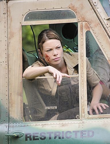 Lori Weston (Lauren German) qui est légèrement amochée sur le visage, regarde par la fenêtre de l'hélicoptère.