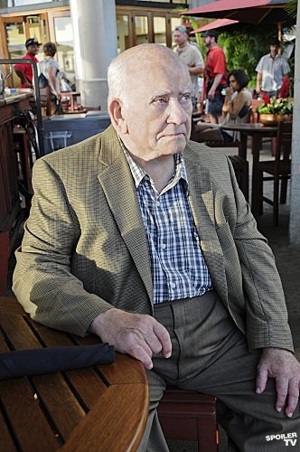 August March (Ed Asner) patiente à la table d'un restaurant.