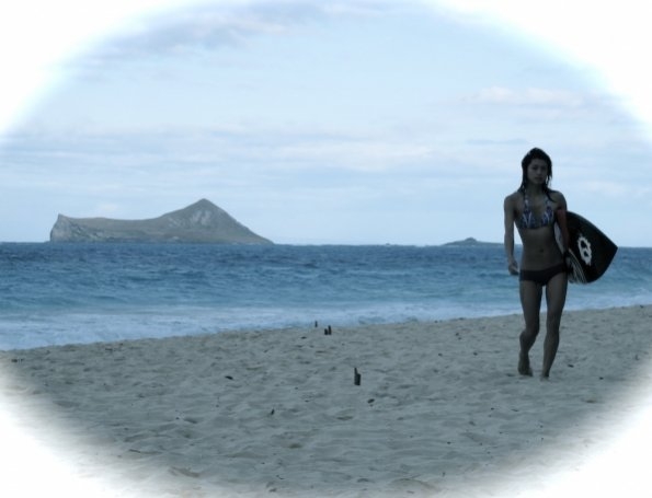 Kono (Grace Park) en maillot de bain sur la plage avec sa planche de surf à la main.