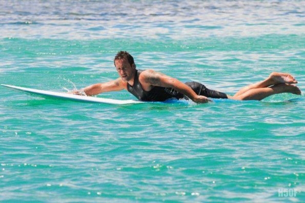 Steve McGarrett (Alex O'Loughlin) sur une planche de surf.