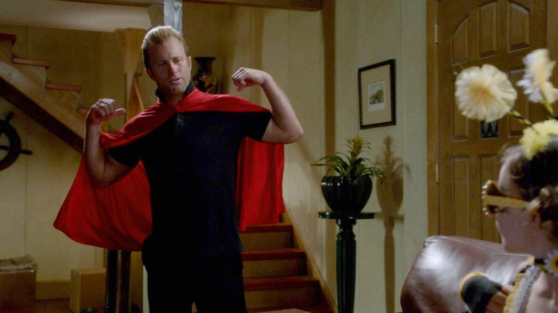 Danny (Scott Caan) porte une cape rouge sur son dos.