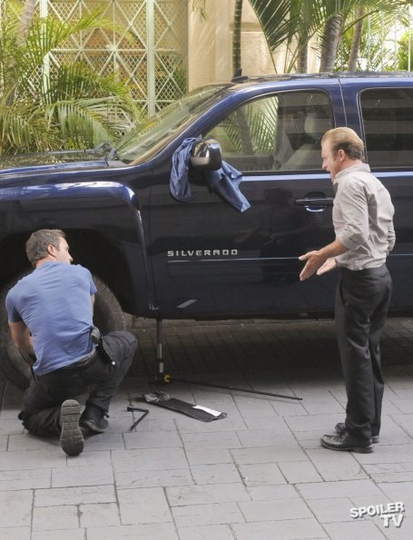 Steve McGarrett (Alex O'Loughlin) est en train de réparer son pneu de voiture tandis que Danny Williams (Scott Caan) s'énerve.