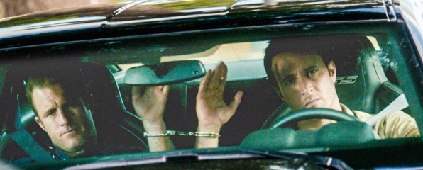 McGarrett (Alex O'Loughlin) et Danny (Scott Caan) sont menottés l'un à l'autre dans la voiture de ce dernier.