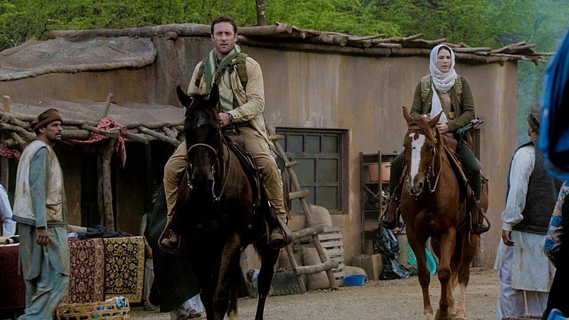 Steve (Alex O'Loughlin) et Catherine (Michelle Borth) arrivent dans un village en Afghanistan sur des chevaux.