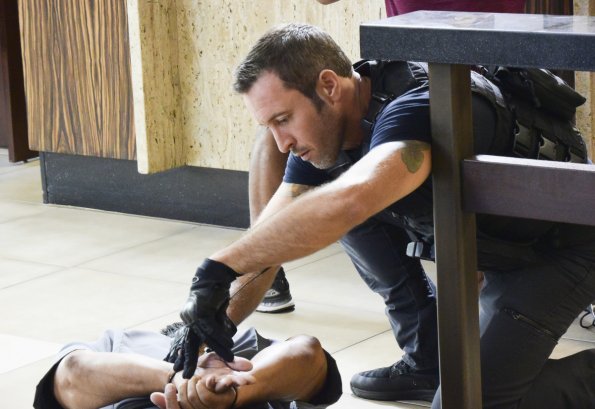 Steve McGarrett (Alex O'Loughlin) aide un otage qui a les mains ligotés.