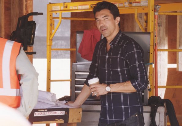 Sur un bâtiment en construction, Adam Noshimuri (Ian Anthony Dale) est en train de boire un café.