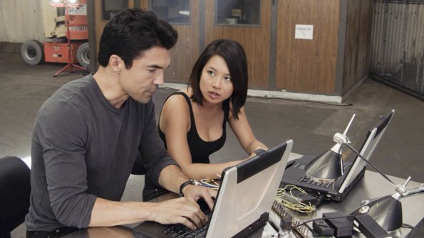 Tout en travaillant sur les ordinateurs, Adam (Ian Anthony Dale) et Jessie (Christine Ko) discutent de leur mission consistant à démanteler le crime organisé.