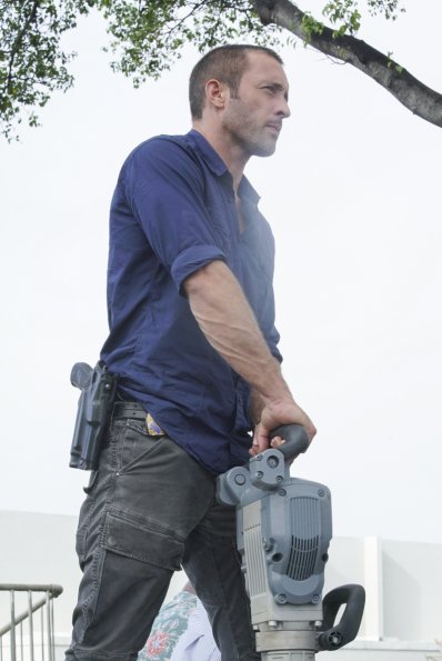 Steve McGarrett (Alex O'Loughlin) tient un marteau-piqueur entre ses mains.