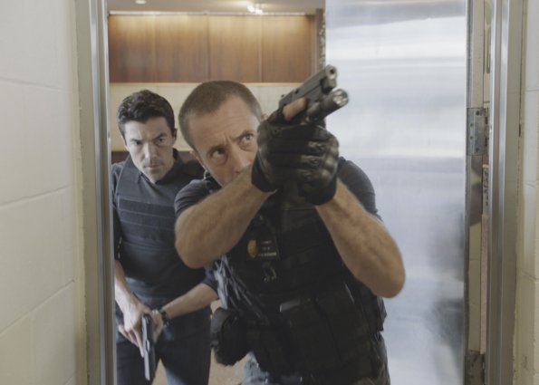 McGarrett (Alex O'Loughlin) et Adam (Ian Anthony Dale) entrent dans un bâtiment, armés.