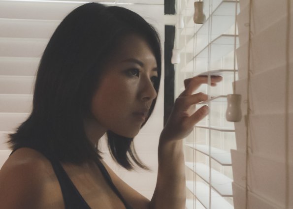 Jessie Nomura (Christine Ko) est en train d'observer quelque chose par la fenêtre...