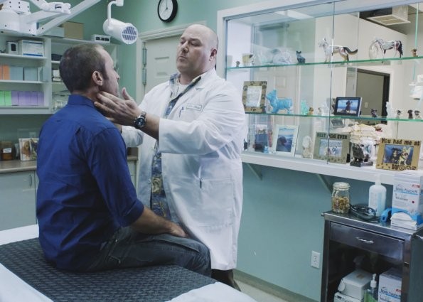 Dr. Shaw (Will Sasso) examine Steve McGarrett (Alex O'Loughlin).
