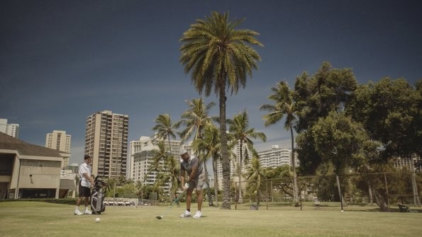 Au loin, Lou Grover (Chi McBride) joue une partie de golf.
