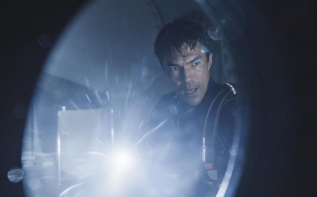 Adam (Ian Anthony Dale) se déplace dans le laboratoire sous-marin avec une lampe torche.