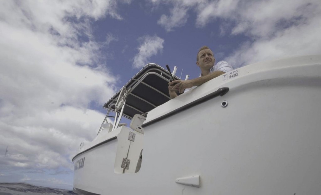 Danny (Scott Caan) patiente sur un bateau avec un téléphone satellite à la main.