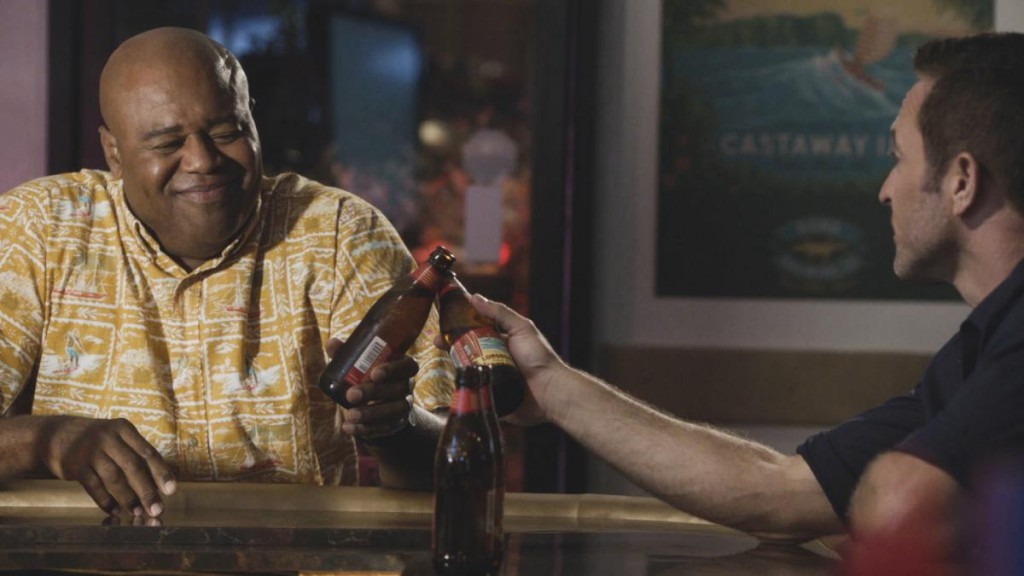 Grover (Chi McBride) et McGarrett (Alex O'Loughlin) trinquent avec des bouteilles de bières.
