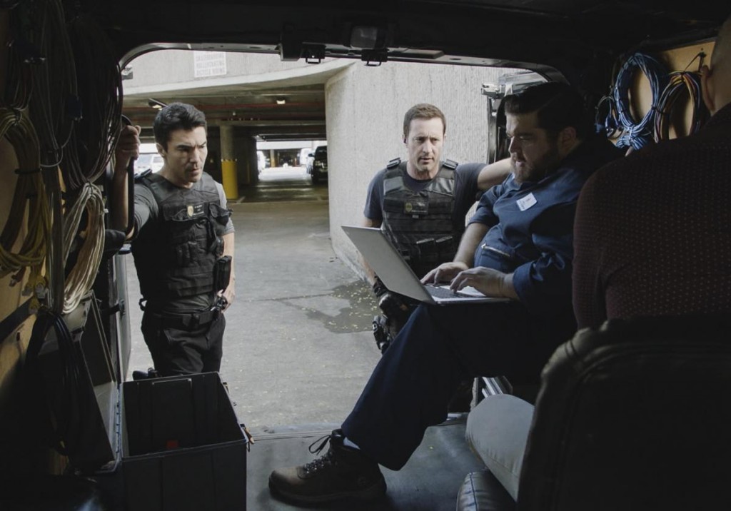Dans un van, Jerry (Jorge Garcia) pianote sur un ordinateur portable sous le regard de Steve (Alex O'Loughlin) et Adam (Ian Anthony Dale).