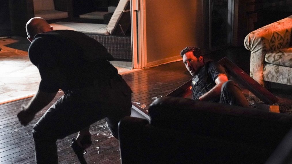Steve (Alex O'Loughlin) est allongé sur le sol alors que son ennemi, armé, se relève.