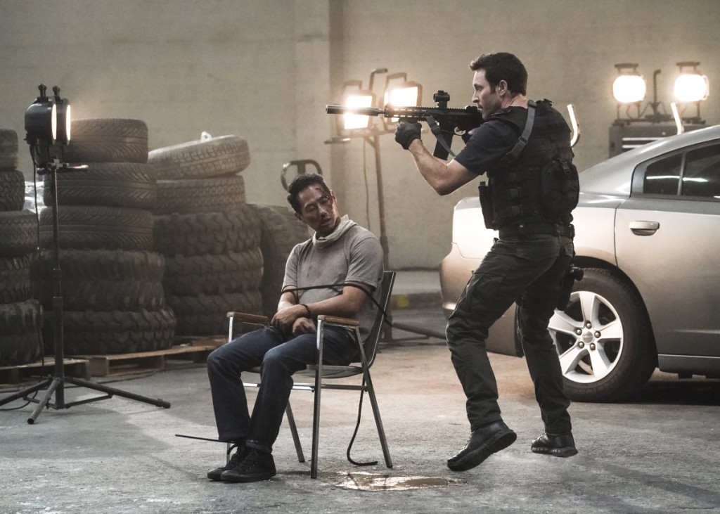 Steve (Alex O'Loughlin) assure la protection d'un homme blessé qui est ligoté à une chaise.