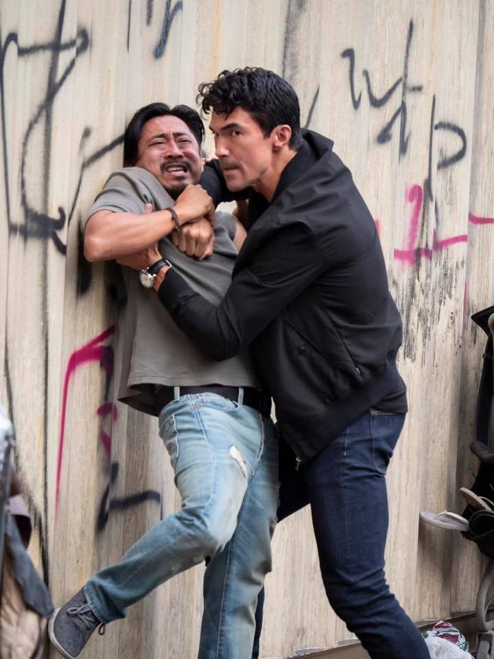 Adam (Ian Anthony Dale) menace Bodhi (Dionysio Basco) dans une ruelle.