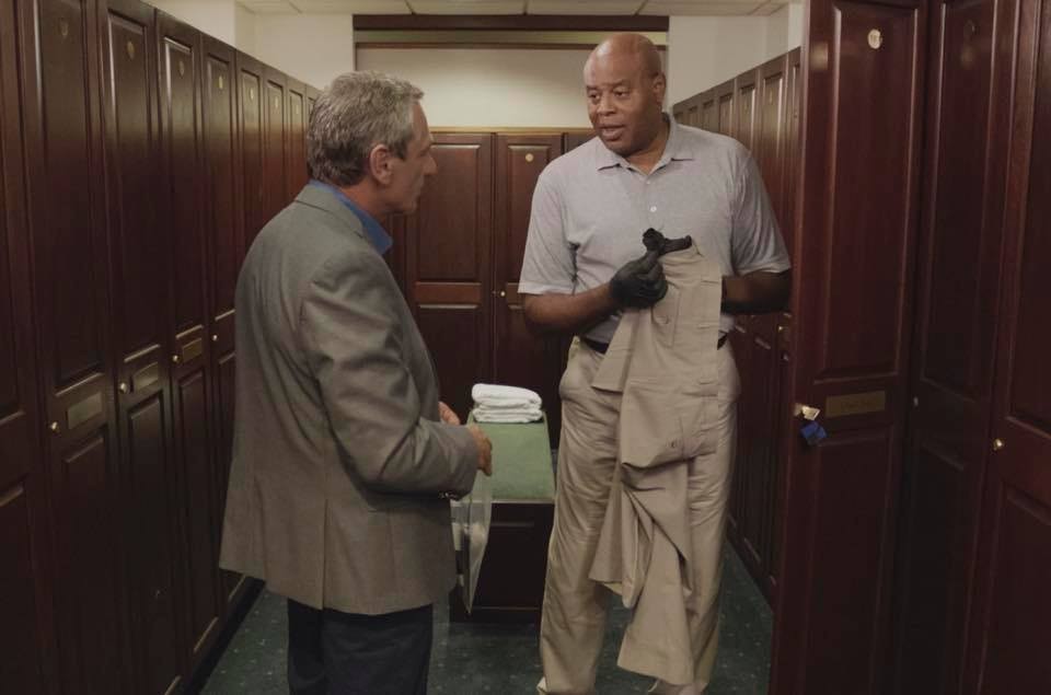 Grover (Chi McBride) discute avec un homme dans les vestiaires d'un terrain de golf.