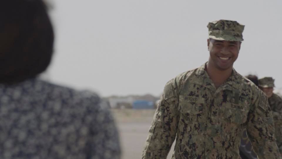 Junior (Beulah Koale) revient en tenue de militaire et avec un grand sourire.