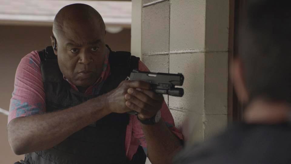 Grover (Chi McBride) tient une arme entre ses mains.