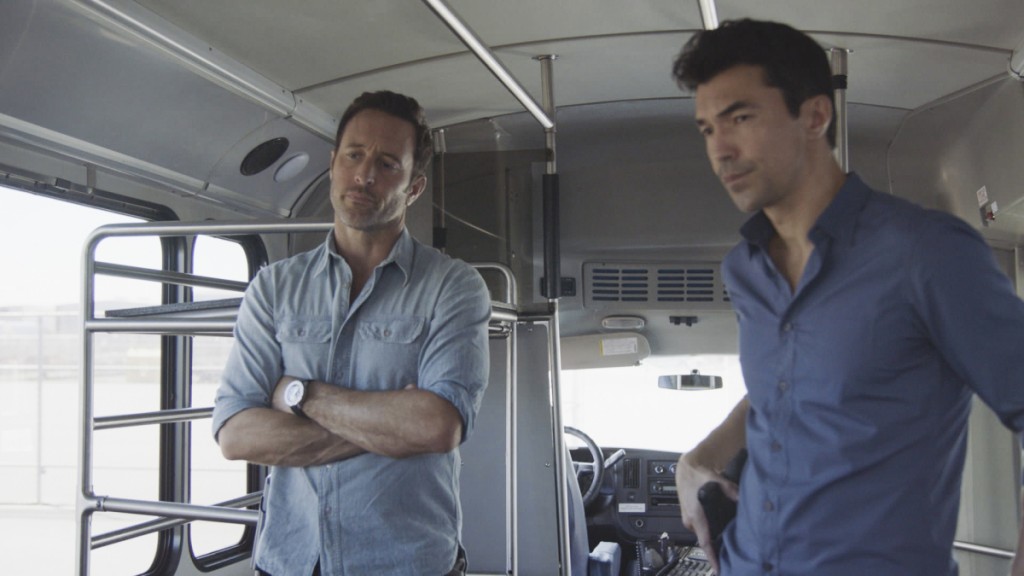 Steve (Alex O'Loughlin) et Adam (Ian Anthony Dale) interrogent un homme dans un bus.