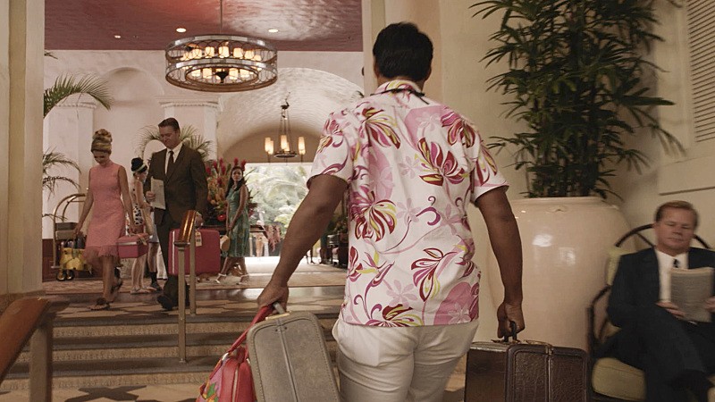 1963 - Un homme en chemise hawaiienne porte des bagages dans un hôtel de luxe.